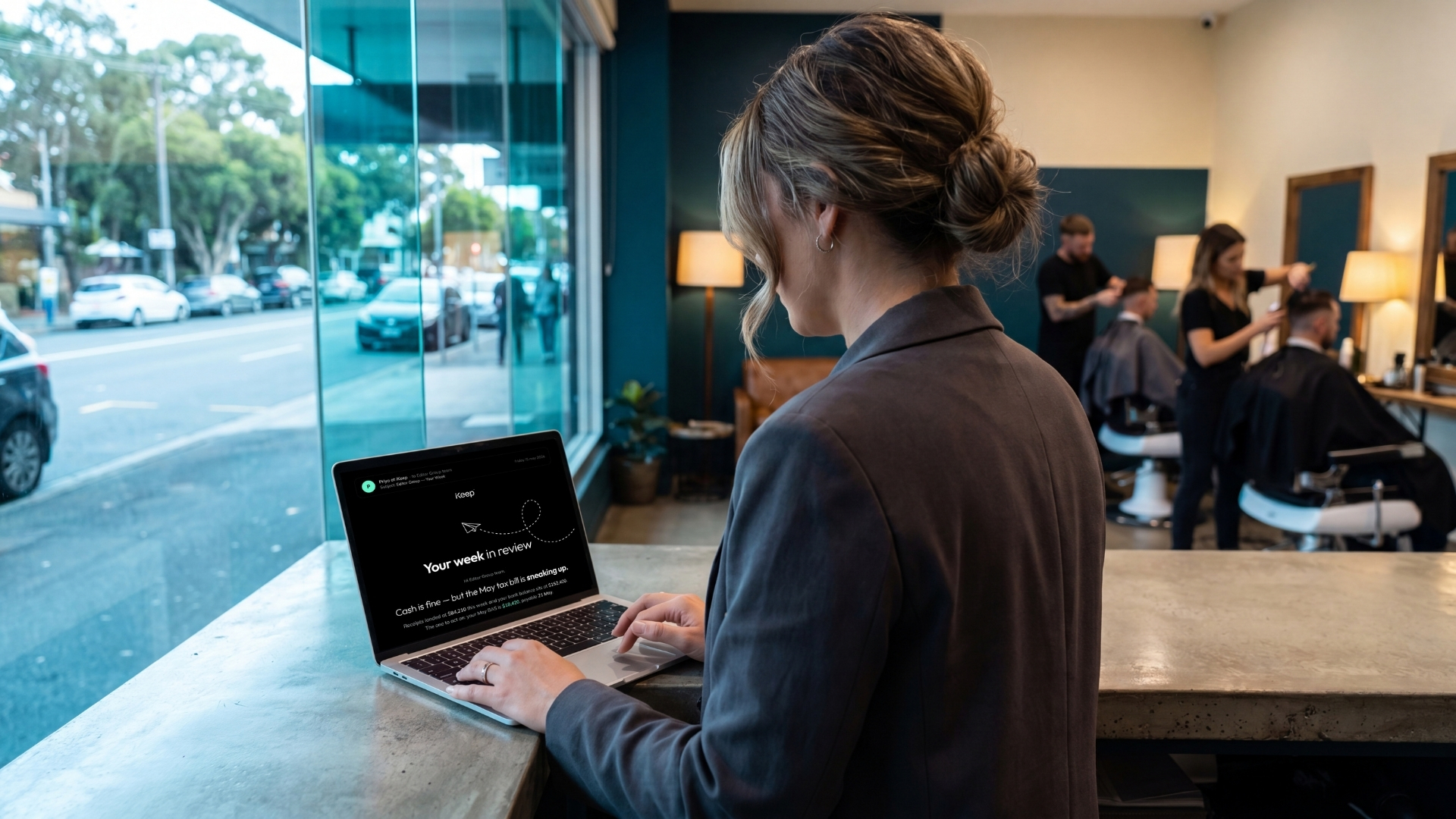 A business owner reviewing her weekly iKeep email on a laptop at her salon counter